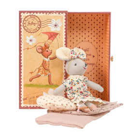 Stuffed cloth mouse toy in a floral dress and headband bow sitting on bedding with a matching open gift box