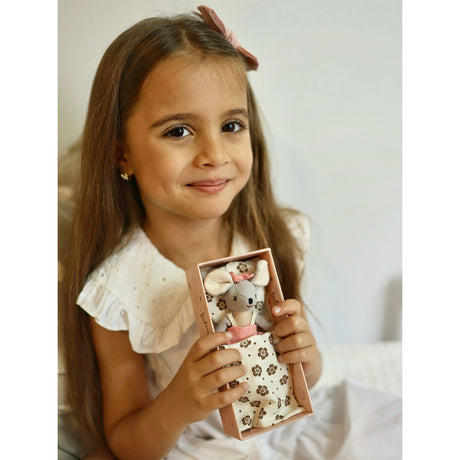 Young girl holding a small soft toy mouse in a decorative box against a plain background