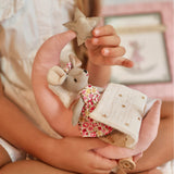 Child holding a small stuffed mouse with a star and a blanket