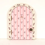 Pink fairy door with decorative patterns and metel knob on a white background