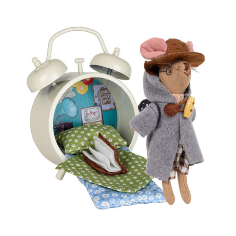 Small mouse doll with a coat and hat standing next to an alarm clock that has been repurposed as a bed.