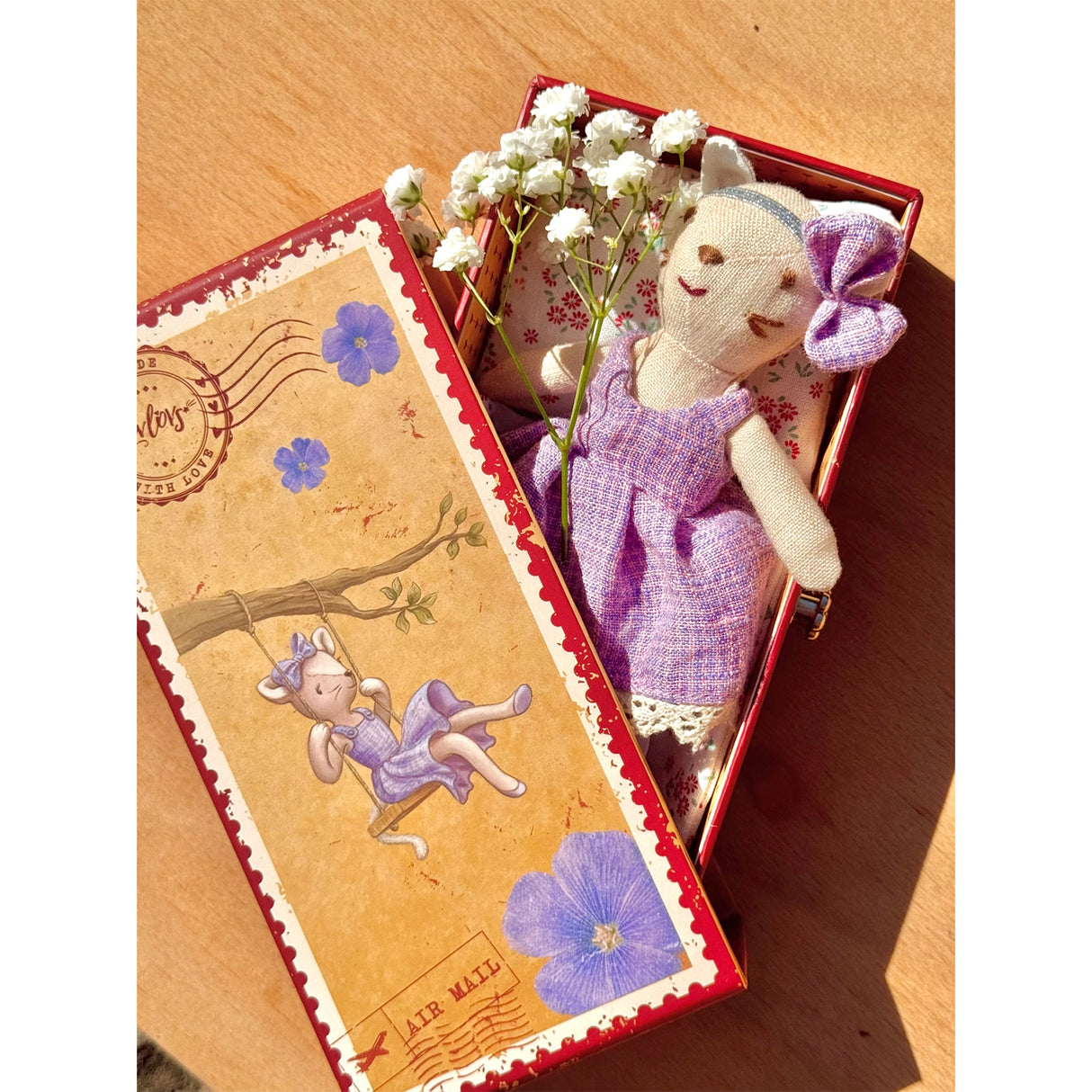 Soft cat toy in a decorative box with flowers on a wooden surface