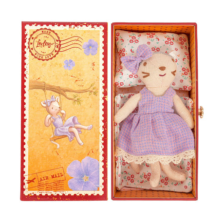 Stuffed cat toy in a purple dress inside an open box with decorative interior, featuring an illustration of a cat on a swing on the cover.