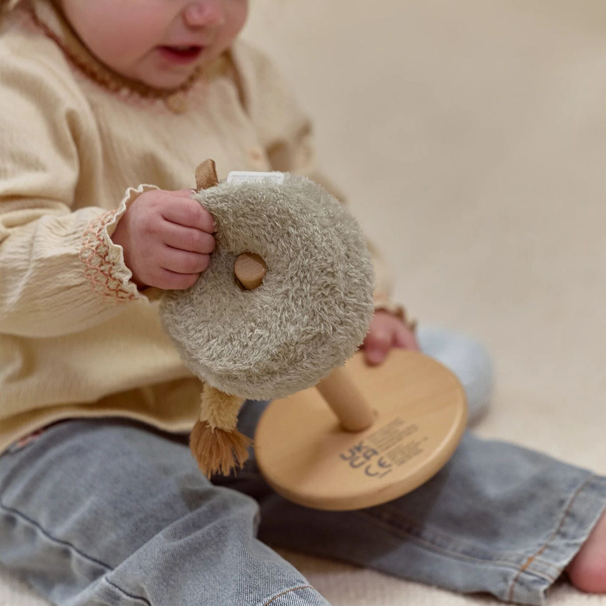 Child holding a wooden stacking toy with a soft ring