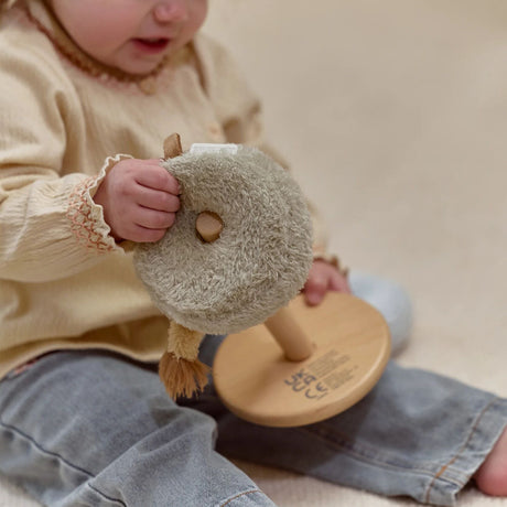 Child holding a wooden stacking toy with a soft ring