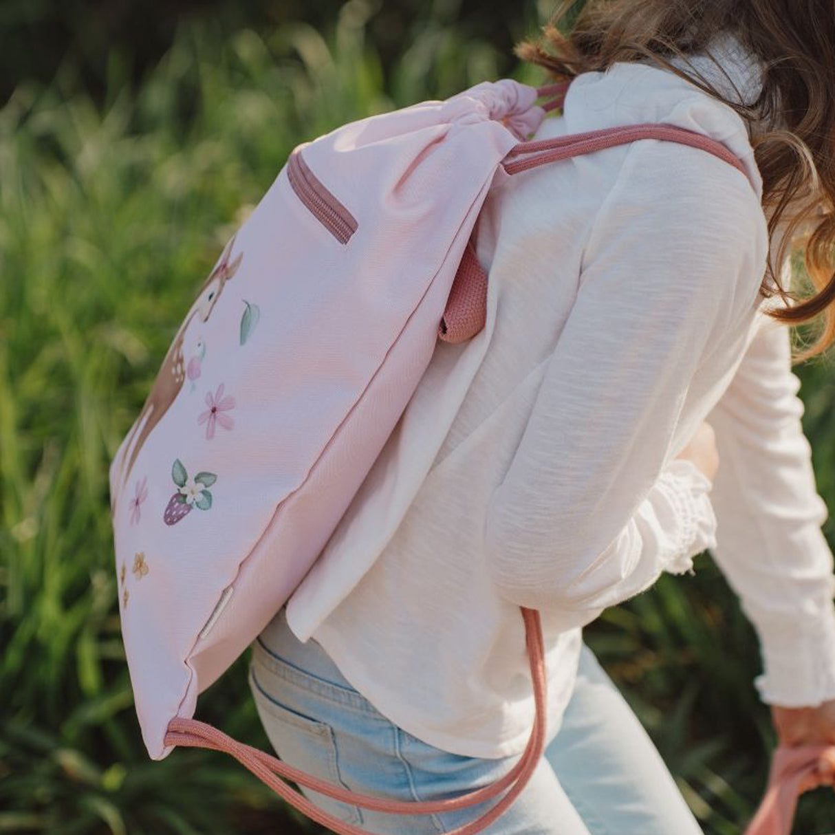 Child wearing a pink backpack with floral designs outdoors