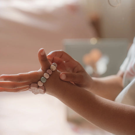 Close-up of hands wearing colorful wooden bracelets with a blurred background