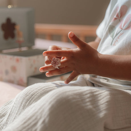 Child wearing a ring with a floral design in a cozy indoor setting