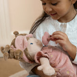 Child playing with a soft doll wearing a pink outfit