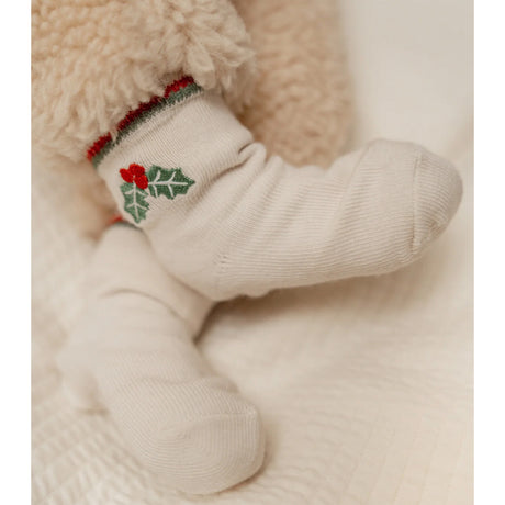 Baby sock with holly design on a soft beige background