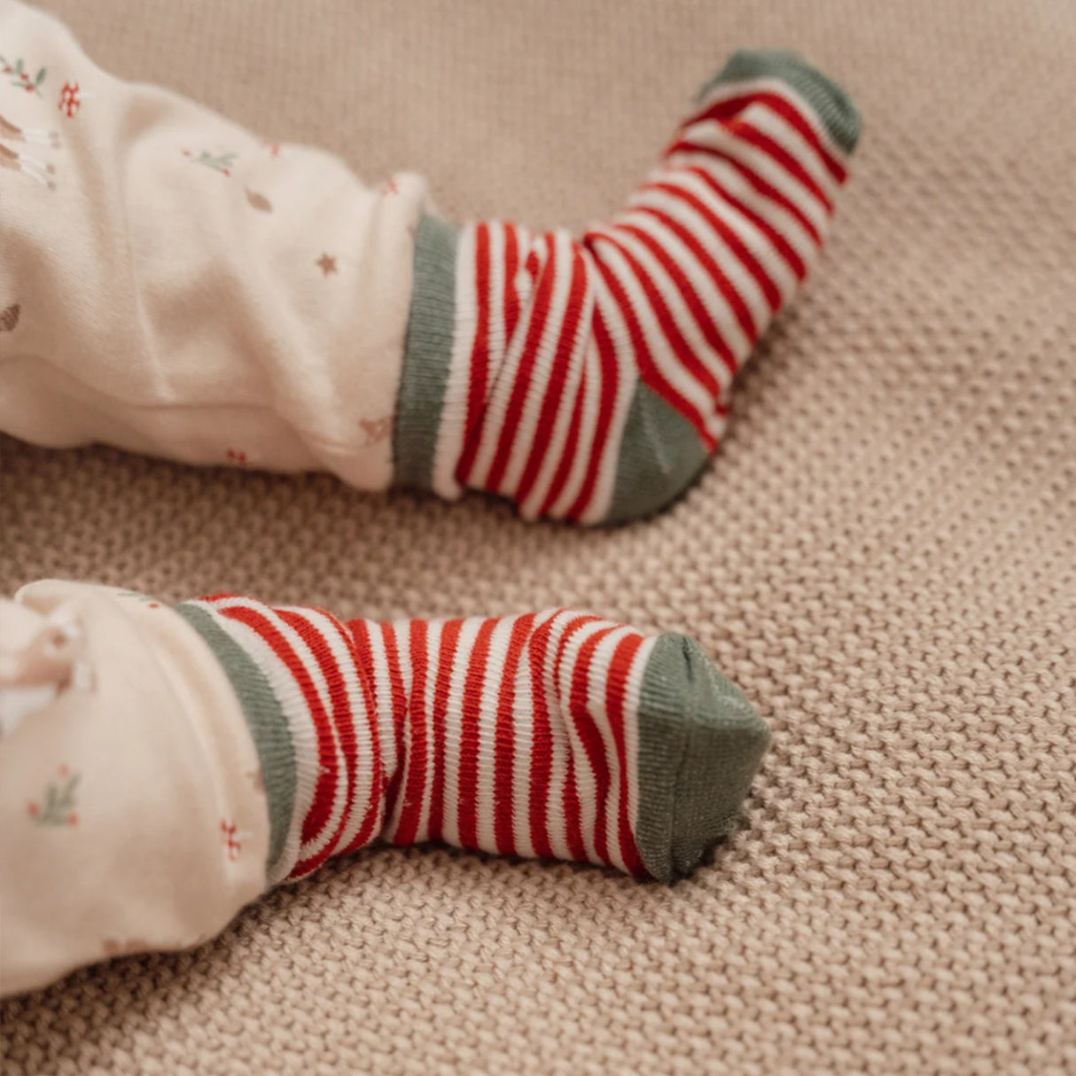 Red and white striped socks on a child's feet with a beige background