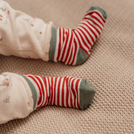 Red and white striped socks on a child's feet with a beige background