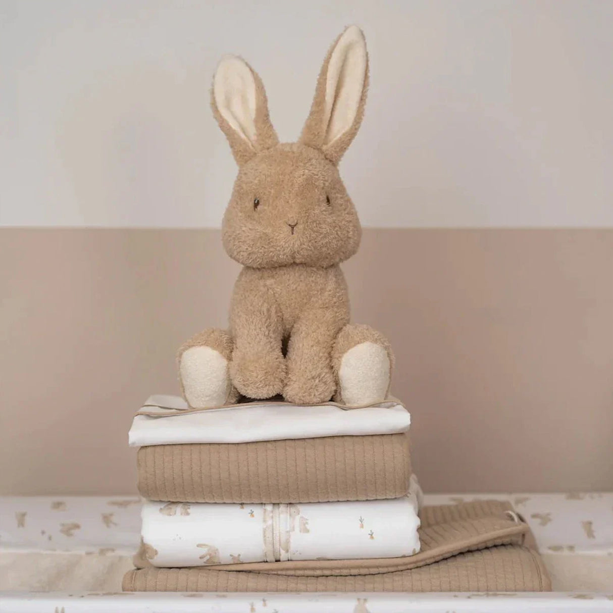 Plush rabbit toy on a stack of folded towels with a neutral background