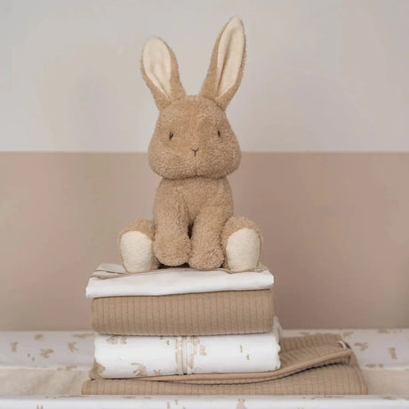 Plush rabbit toy on a stack of folded towels with a neutral background