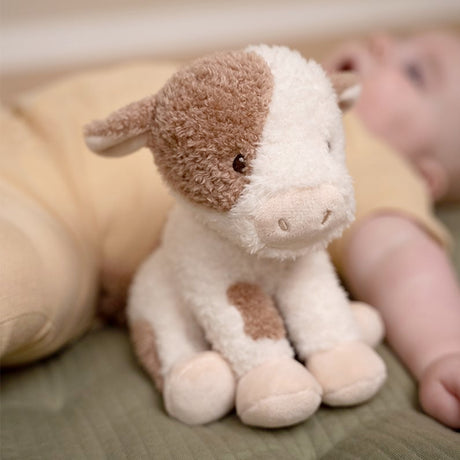 Little Dutch Plush toy cow with brown spots next to a baby