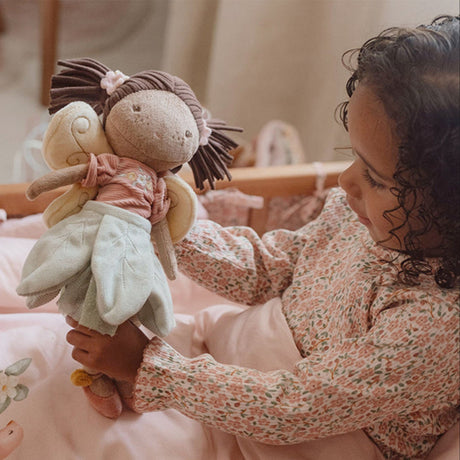 Child holding a plush fairy doll toy in a cozy bedroom setting