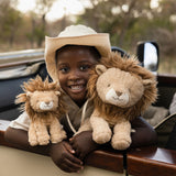 Child holding two lion plush toys with a safari vehicle in the background