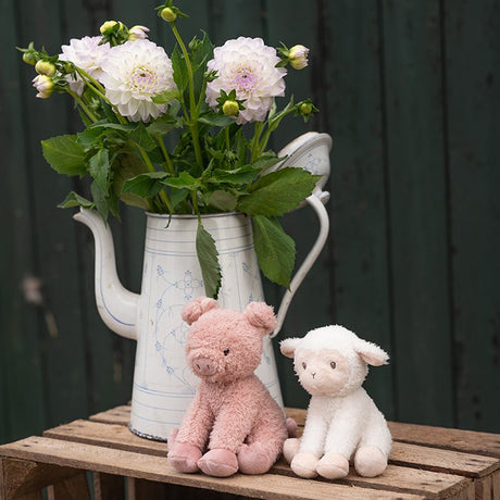 Soft toy Pig and lamb on a table next to a jug of flowers