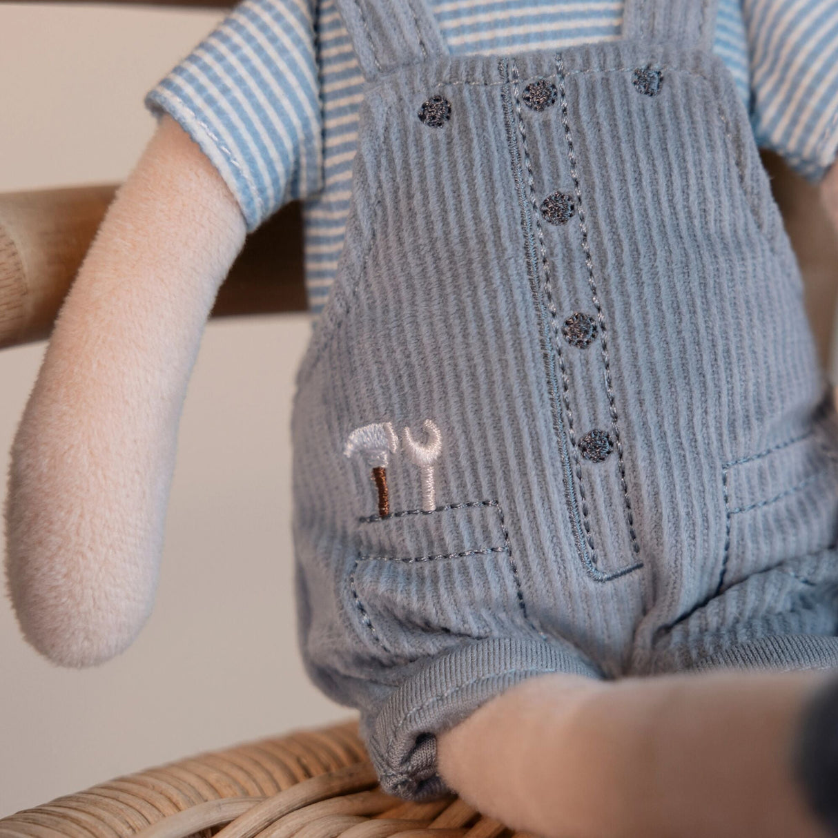 Soft boy doll in blue corduroy overalls with embroidered tools in his pocket