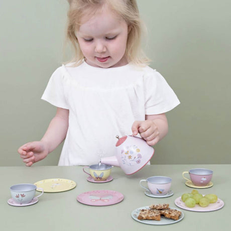 Child playing with a tea set on a table against a plain background