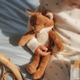 Child holding a plush fox toy on a light blue blanket