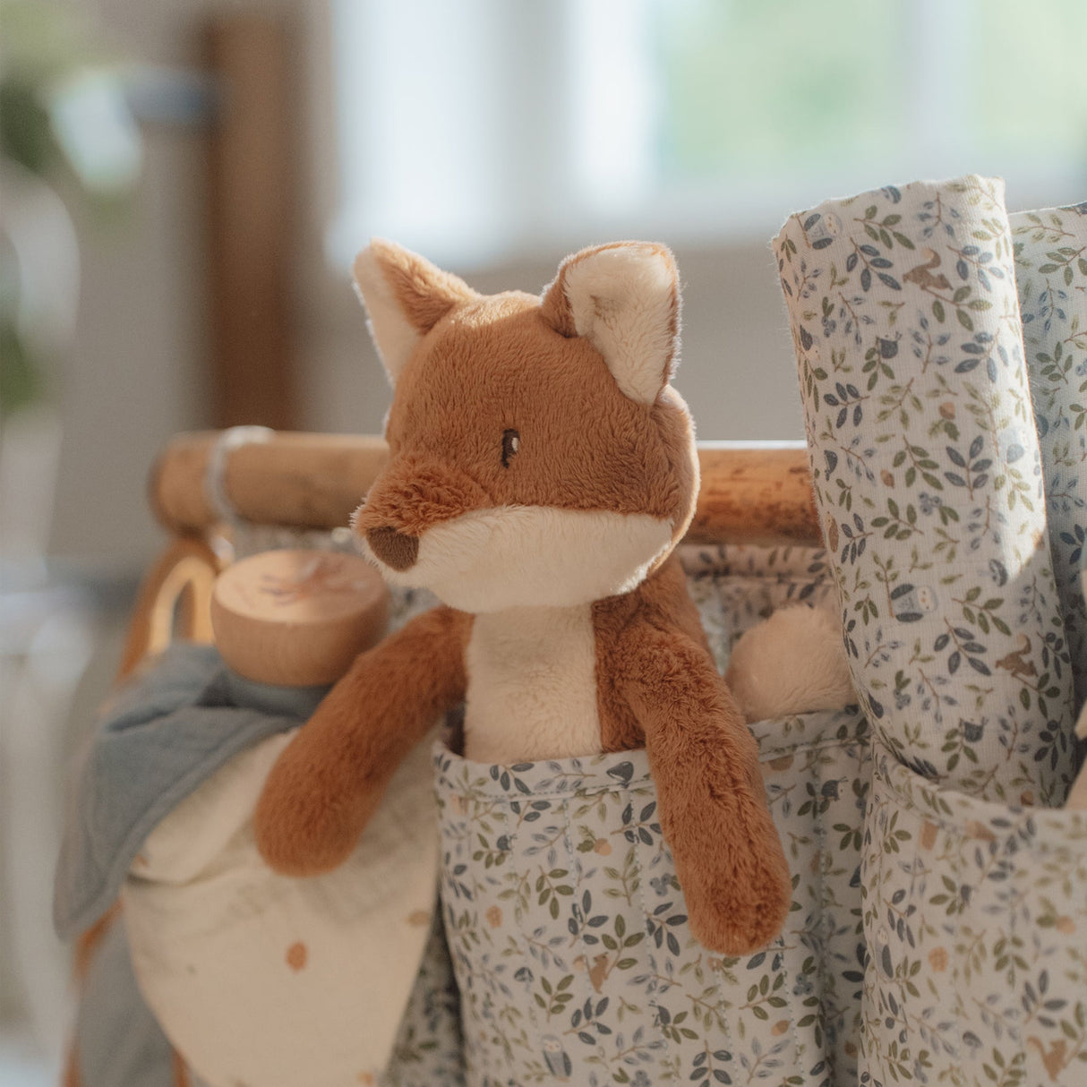 Plush fox toy in a floral-patterned bag with a blurred background