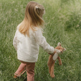 Child holding a plush toy in a grassy field