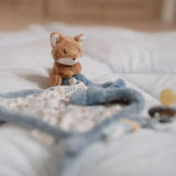 A small plush fox toy attached to a soother on a bed