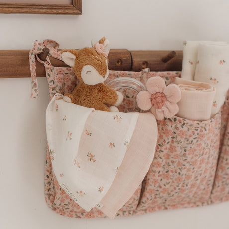 Floral-patterned basket with a plush toy and decorative items on a white surface.