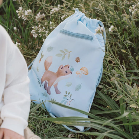 Little Dutch Forest Friends Light blue drawstring bag with nature-themed design held by a hand in a grassy field