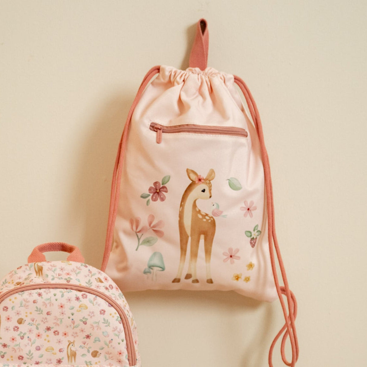Pink drawstring bag with deer design on a beige background