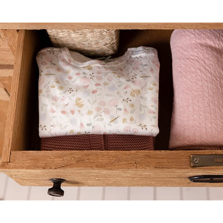 Little Dutch floral baby bodysuit folded in an open wooden drawer with soft pink blanket