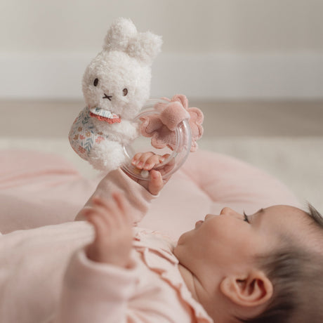 Baby holding a Miffy soft toy rattle with a blurred background