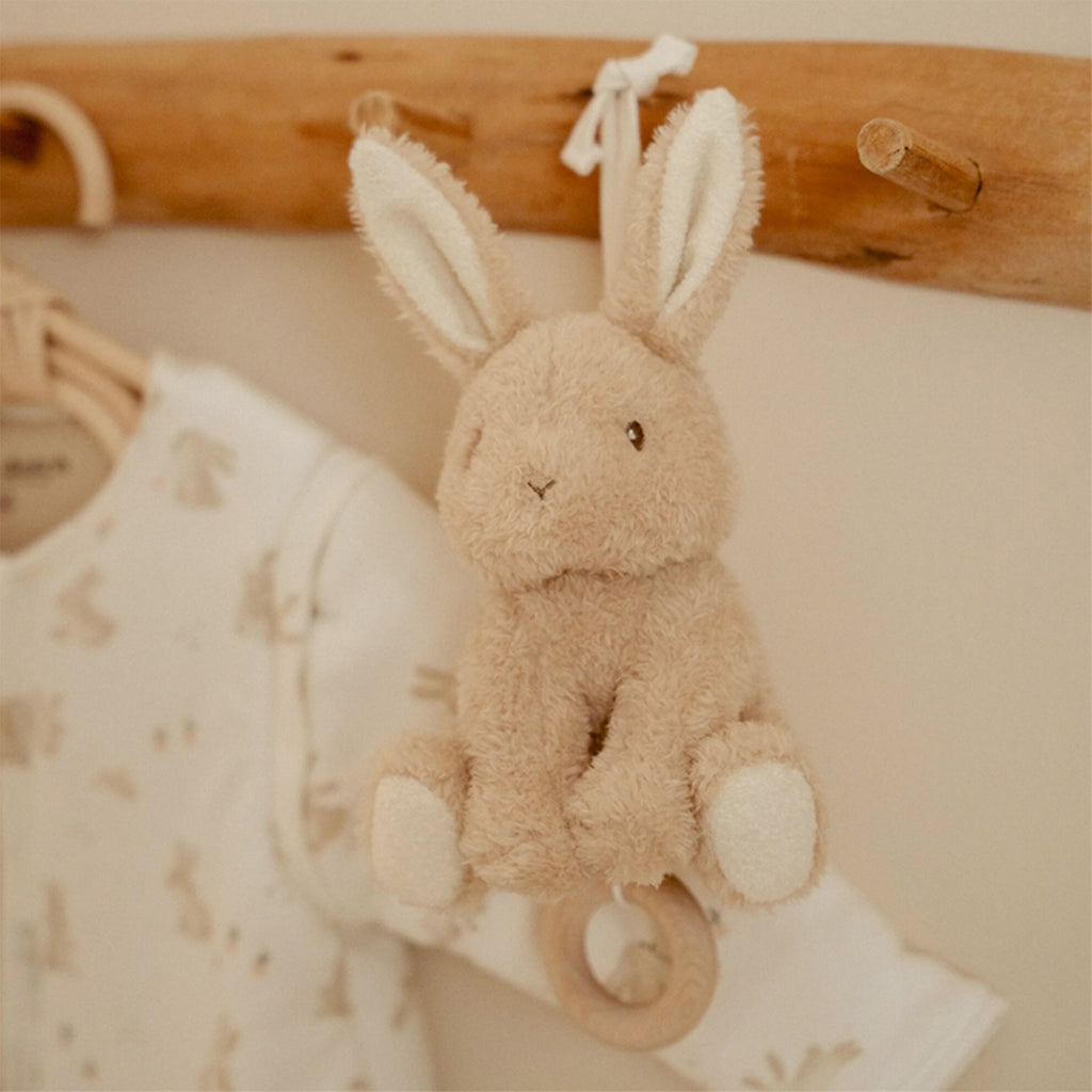 Little Dutch Plush bunny toy hanging on a wooden rack with baby clothes in the background