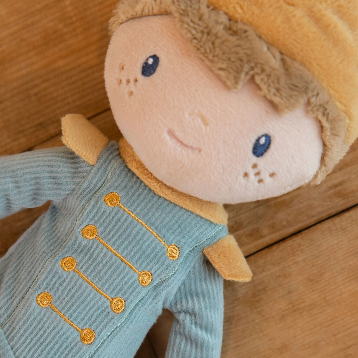 Close-up of Little Dutch Prince Jim Doll showing embroidered gold button detail on teal ribbed jacket