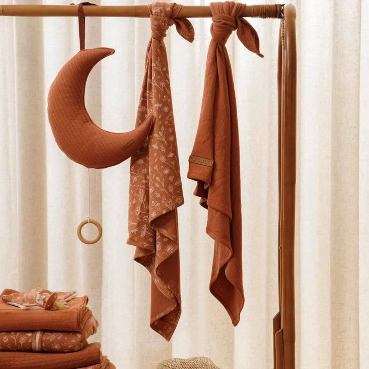Little Dutch rust cotton swaddle cloths hanging on a wooden baby clothes rail with muslin swaddles and moon pull