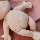 Soft baby doll with a nappy on a pink textured background