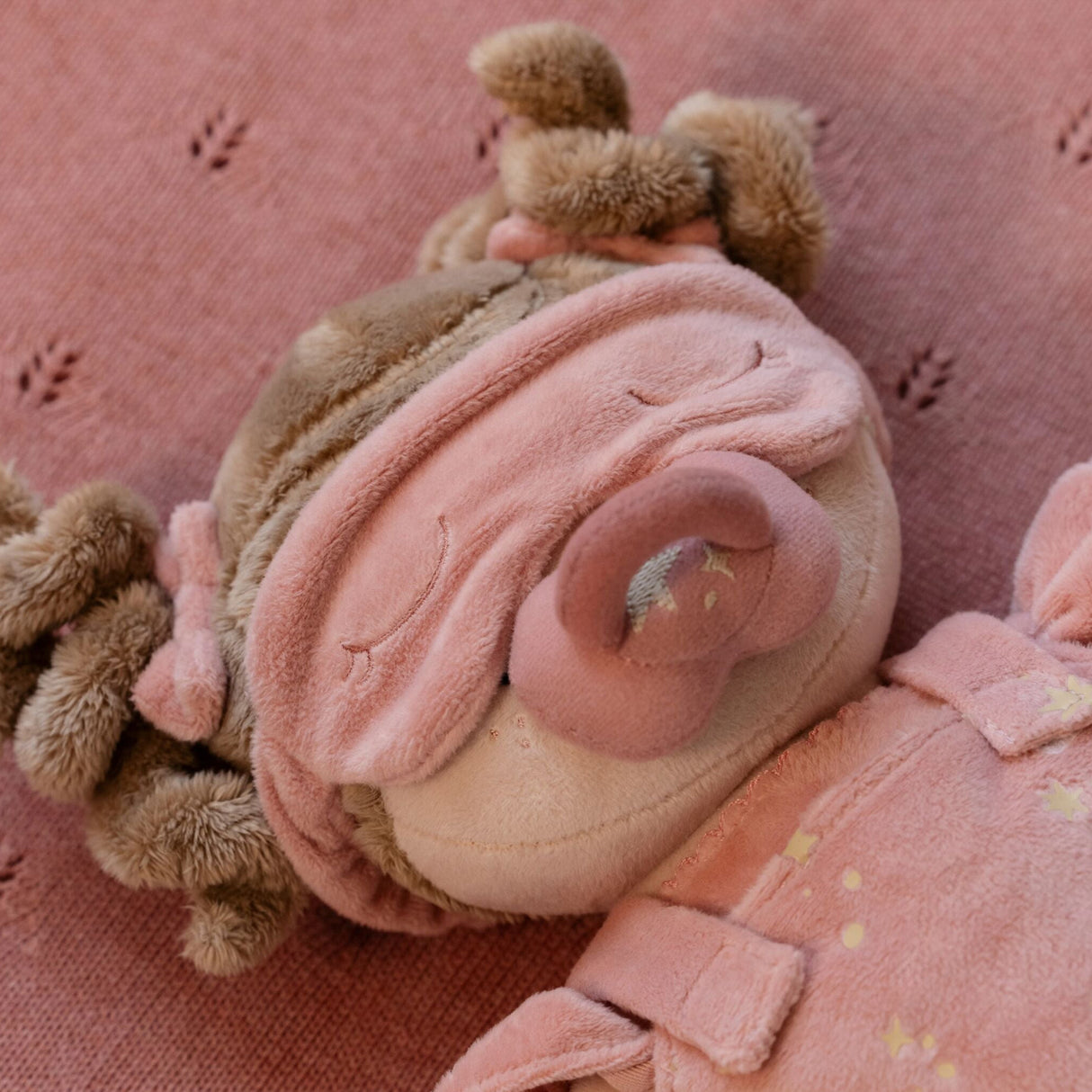 Soft doll with pink bows in hair, sleeping mark and dummy on a pink background