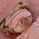Soft doll with pink bows in hair, sleeping mark and dummy on a pink background