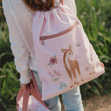 Child wering pink drawstring bag with a deer design outdoors.