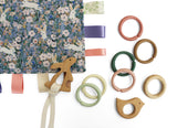 Colourful baby teething rings and soft taggy comforter with floral and rabbit pattern on a white background