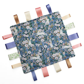 Fabric taggy blanket with rabbit and floral pattern on a white background
