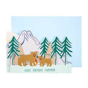 Birthday card with bears, trees, and mountains on a light blue background