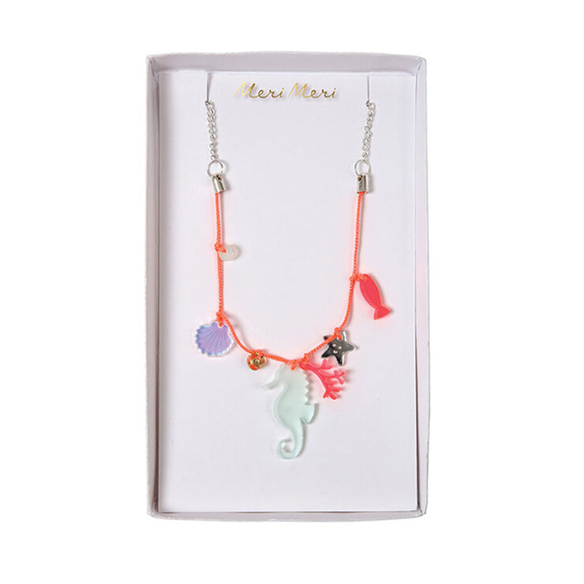 A colorful acrylic necklace with sea creature charms including a starfish, sea horse, and shell, suspended on a neon lace with a silver tone chain and clasps, presented in a clear packaging with 'Meri Meri' branding at the top.