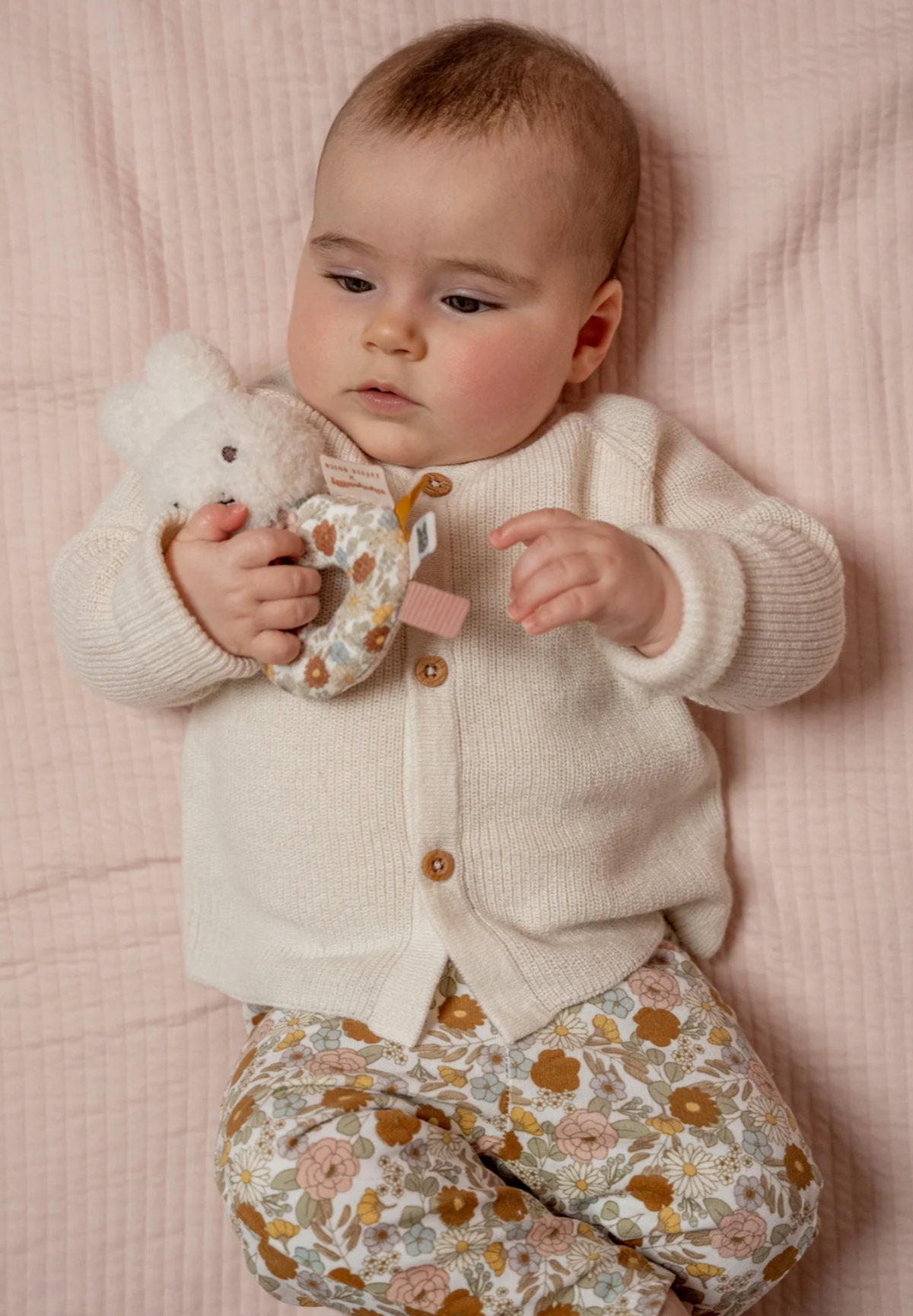 Baby lying on pink blanket holding Little Dutch Miffy Vintage Flowers ring rattle