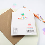 Mifkins card packaging with a brown envelope and colourful pen on a light background