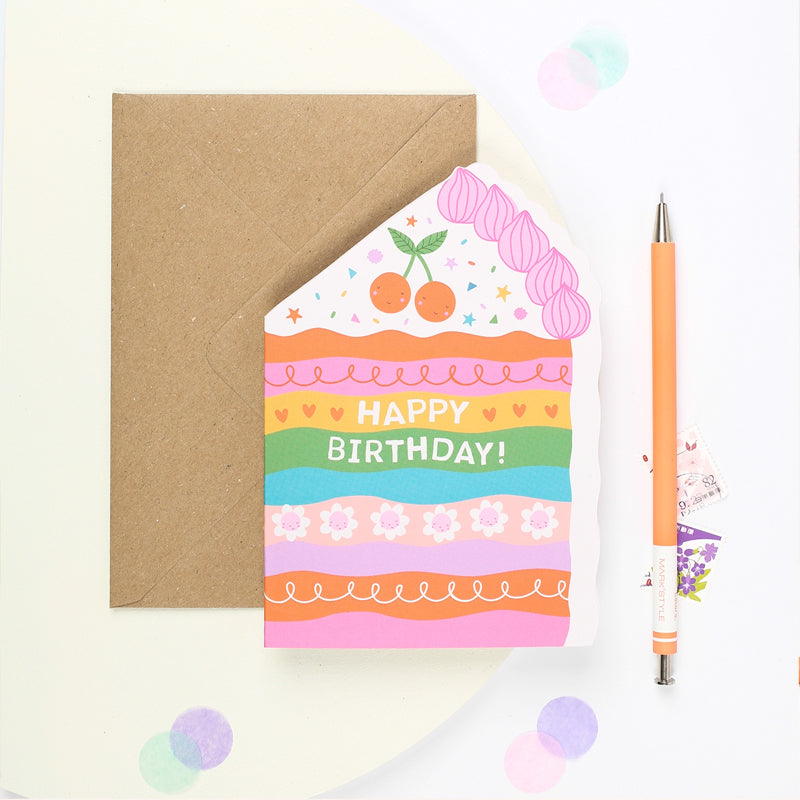 Colorful birthday card with a cake design and 'Happy Birthday!' text, next to a brown envelope.