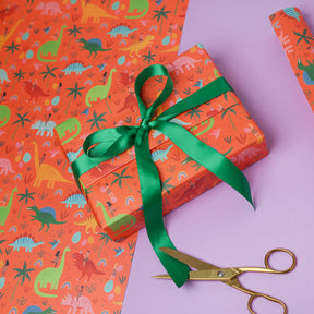 Gift box with dinosaur pattern and green ribbon on a purple background