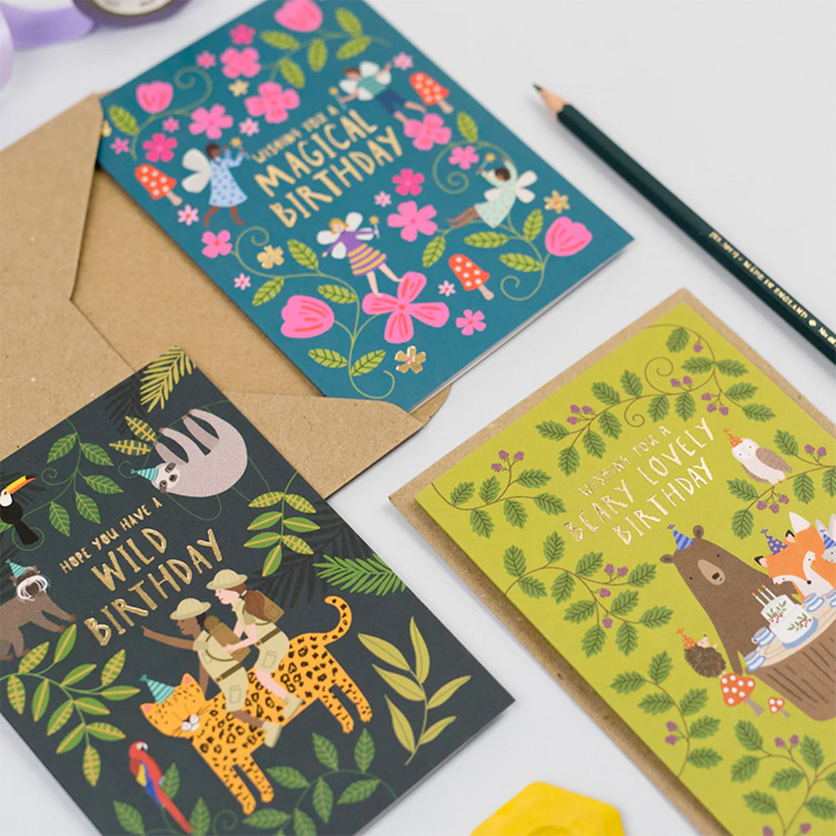 Three colorful birthday cards with illustrations on a white surface.