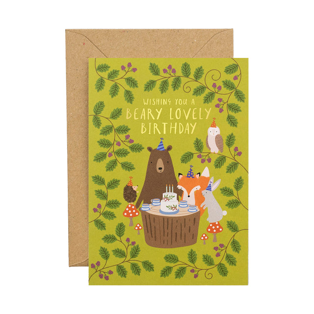 A green Birthday card with illustrated bear, fox, hedgehog, owl and rabbit around a cake on a tree stump,  with leaves surrounding them. Comes with a brown envelope.